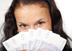 A girl holding money in front of her face with a glint in her eyes