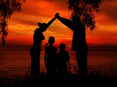 Parents hold their arms over their children with an orange/red sky in the background