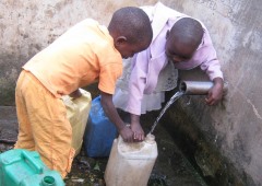 Water Two boys in Africa collecting pipe water into plastic containers